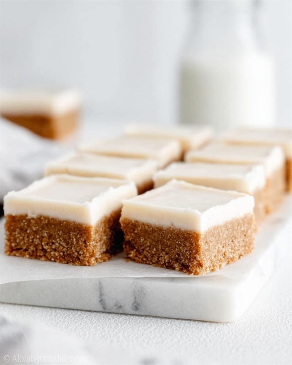 A white marble tray holds two rows of rectangular, light brown bars with a soft, creamy white layer on top. The bars look dense and thick, with the bottom layer having a coarse, crumbly texture and the top layer smooth and even. The background is a white marbled surface with a blurred glass bottle behind the tray, creating a clean and bright setting. The bars are neatly cut and lined up close together, highlighting their clear two-layer structure. Photo taken with an iphone --ar 4:5 --v 7