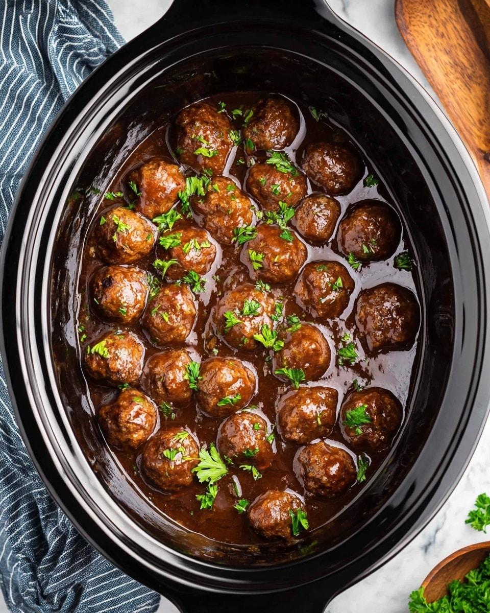 A close-up top view of a black crockpot filled with about twenty brown meatballs sitting in a thick, dark brown sauce. Small bright green parsley leaves are sprinkled over the meatballs and sauce to add a fresh touch. A white marbled surface can be seen under the crockpot, with a striped blue and gray cloth partially visible to the left and part of a wooden dish visible to the right. photo taken with an iphone --ar 4:5 --v 7