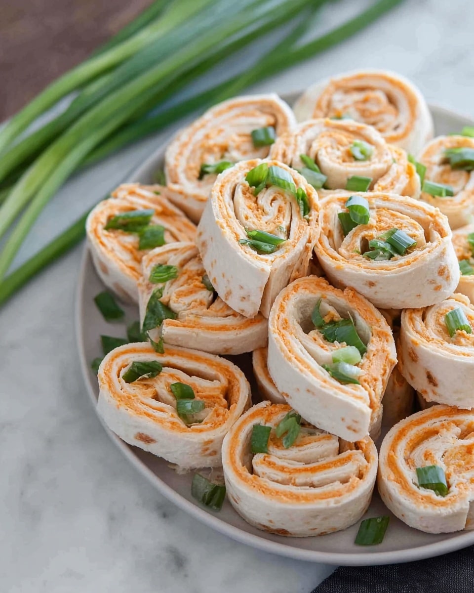 A plate full of small rolled pinwheel sandwiches is shown, each with three visible layers: the outer layer is a soft, white tortilla wrap, the middle layer is a smooth orange spread, and thin green onion slices are tucked inside the roll and sprinkled on top. The rolls are stacked on a white plate, placed on a white marbled surface with some whole green onions beside it. The texture of the wraps is soft and smooth, while the spread looks creamy and slightly textured. photo taken with an iphone --ar 4:5 --v 7