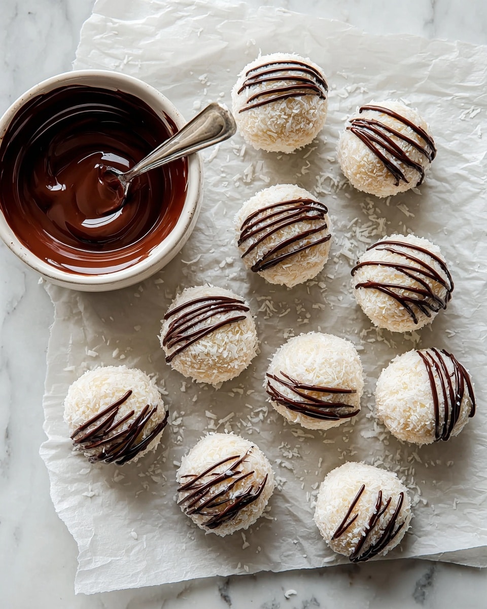 The image shows round white coconut-coated balls arranged on a piece of parchment paper over a white marbled surface. Each ball is evenly covered with shredded coconut, giving a rough texture, and has thin dark brown chocolate drizzles on top in a zigzag pattern. Beside the balls, there is a white bowl with smooth dark melted chocolate inside and on the edges, along with a spoon coated with the chocolate resting in the bowl. The overall look is neat and appetizing with the contrast of white coconut and dark chocolate. photo taken with an iphone --ar 4:5 --v 7