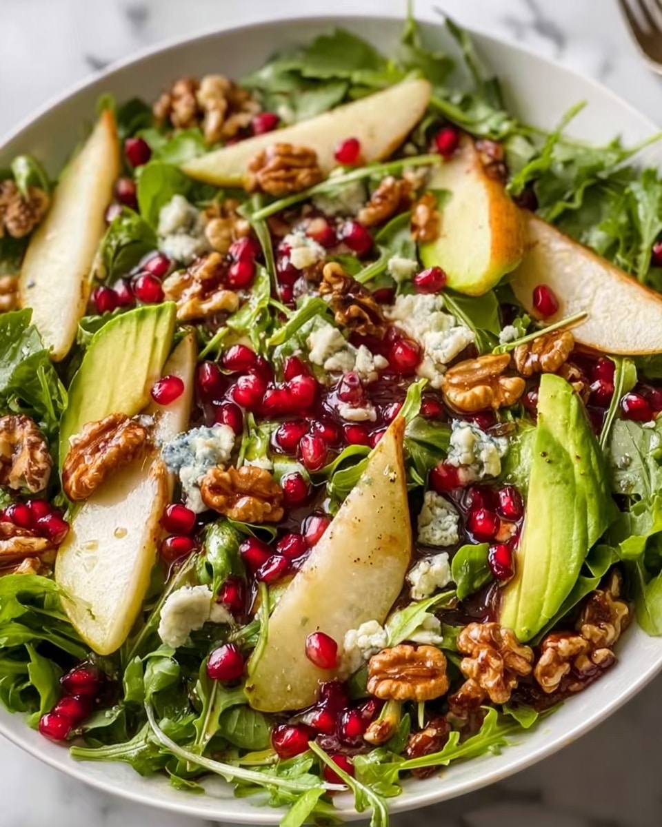 A fresh salad is shown with a mix of green leafy arugula as the base layer spread all over the white round plate. On top, there are thin slices of light green avocado, small pieces of red pomegranate seeds, and chunks of brown walnuts scattered evenly. There are also thin slices of light yellow pear placed throughout. Small bits of blue cheese add a creamy texture, all visible in close detail. The salad looks shiny with a light dressing coating. The scene is set on a white marbled surface. Photo taken with an iphone --ar 4:5 --v 7