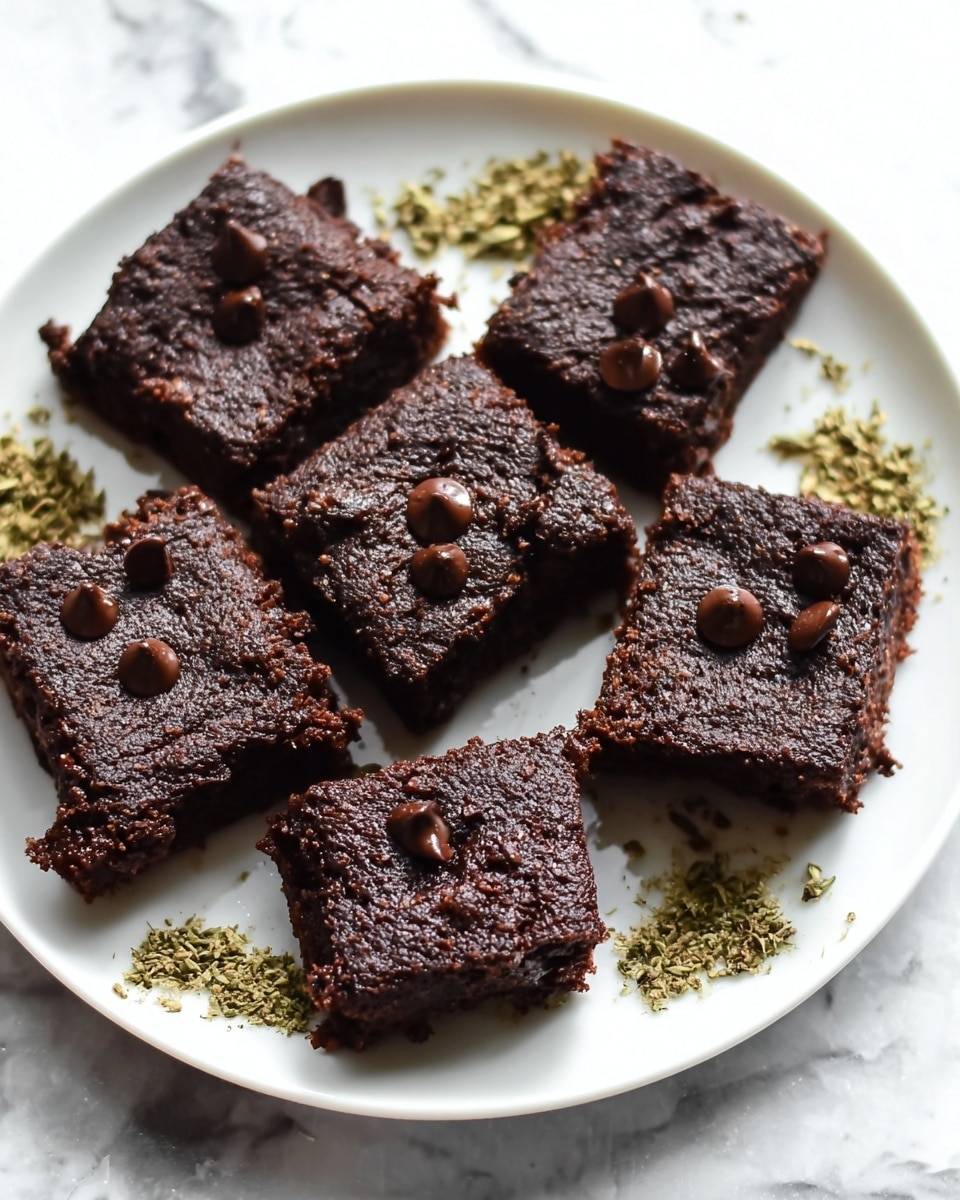 A white plate holds eight square pieces of dark chocolate brownies arranged close together. Each brownie has a rough, slightly crumbly top texture with a few glossy chocolate chips scattered on top, adding shine and contrast. The brownies look thick and dense, with a deep dark brown color. Small pieces of greenish dried herbs surround the brownies, placed sporadically on the plate edges. The whole scene is set on a white marbled textured surface. photo taken with an iphone --ar 4:5 --v 7